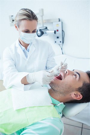 simsearch:6109-08389794,k - Female dentist examining mans teeth in the dentists chair Stockbilder - Microstock & Abonnement, Bildnummer: 400-07939217