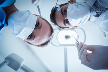 simsearch:400-07938947,k - Low angle view of dentists in surgical masks holding dental tools Photographie de stock - Aubaine LD & Abonnement, Code: 400-07939226
