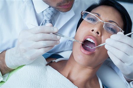 simsearch:6109-08389794,k - Male dentist examining womans teeth in the dentists chair Stockbilder - Microstock & Abonnement, Bildnummer: 400-07939249