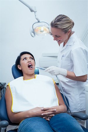 simsearch:6109-08389794,k - Female dentist examining womans teeth in the dentists chair Stockbilder - Microstock & Abonnement, Bildnummer: 400-07939279