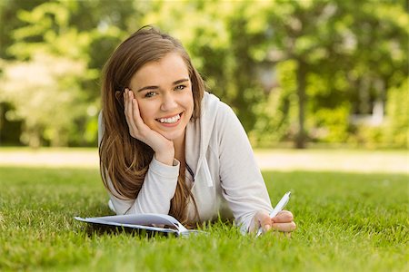 simsearch:400-07939821,k - Smiling university student lying and writing on notepad in park at school Photographie de stock - Aubaine LD & Abonnement, Code: 400-07939640