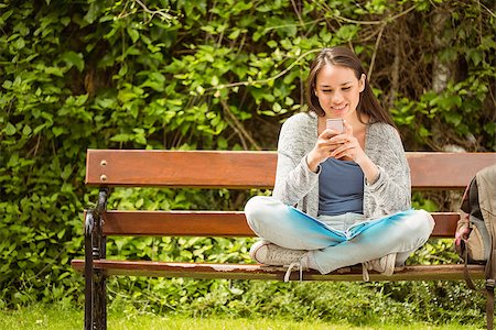 students campus phones - Smiling student sitting on bench text message on her mobile phone in park at school Stock Photo - Budget Royalty-Free & Subscription, Code: 400-07939663