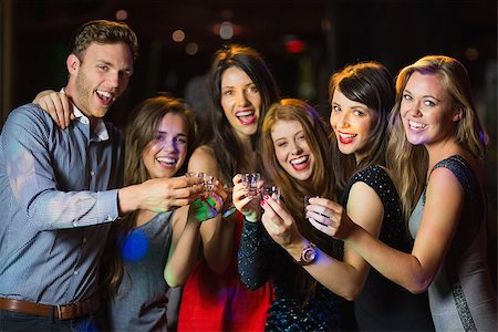 simsearch:400-07939979,k - Happy friends drinking shots smiling at camera at the nightclub Fotografie stock - Microstock e Abbonamento, Codice: 400-07939979