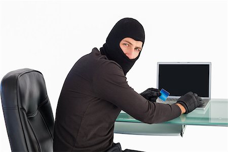 simsearch:400-06803569,k - Burglar shopping online with laptop while looking at camera on white background Stock Photo - Budget Royalty-Free & Subscription, Code: 400-07930084