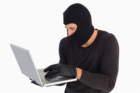 simsearch:400-06803569,k - Focused burglar standing holding laptop on white background Stock Photo - Budget Royalty-Free & Subscription, Code: 400-07930085