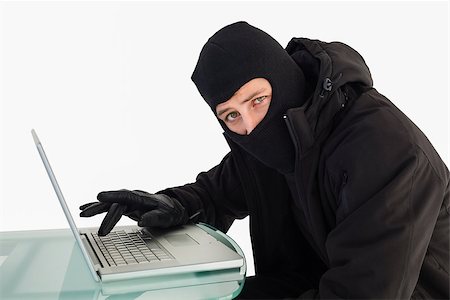 simsearch:400-06881880,k - Burglar using laptop while looking at camera on white background Stockbilder - Microstock & Abonnement, Bildnummer: 400-07930088