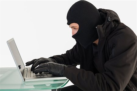 simsearch:400-06803569,k - Robber sitting at desk hacking a laptop on white background Stock Photo - Budget Royalty-Free & Subscription, Code: 400-07930089