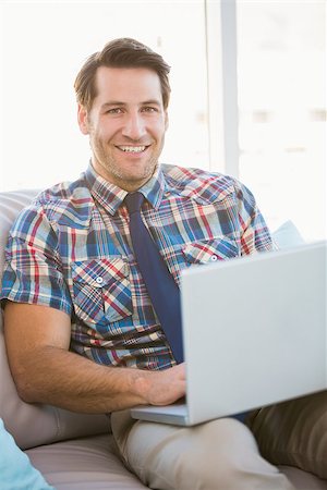 Portrait of man using laptop on couch in bright living room Stock Photo - Budget Royalty-Free & Subscription, Code: 400-07930335