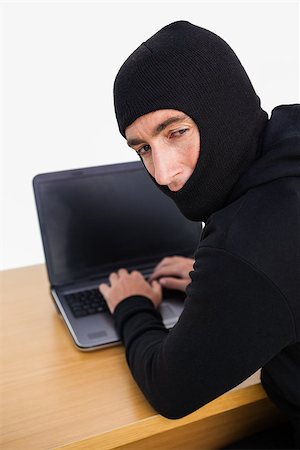 Burglar hacking a laptop and looking behind him on white background Stock Photo - Budget Royalty-Free & Subscription, Code: 400-07930572