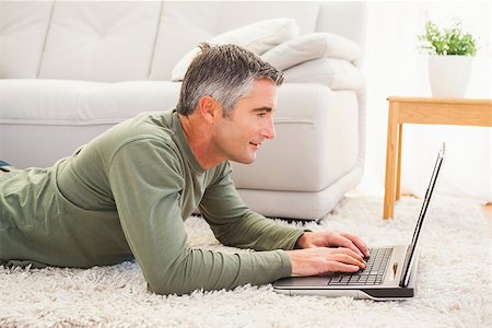 simsearch:400-07916242,k - Smiling man lying on carpet using laptop at home in the living room Foto de stock - Super Valor sin royalties y Suscripción, Código: 400-07930635