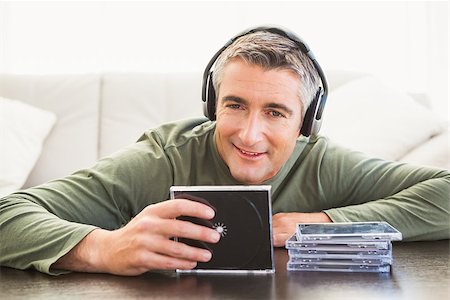 simsearch:400-07916242,k - Smiling man listening music and holding cd at home in the living room Foto de stock - Super Valor sin royalties y Suscripción, Código: 400-07930647