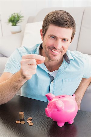 A man showing a pennie with a piggy bank on the coffee table Stock Photo - Budget Royalty-Free & Subscription, Code: 400-07931018
