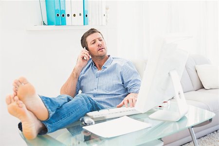 Businessman on the phone using his computer with his feet up in his office Stock Photo - Budget Royalty-Free & Subscription, Code: 400-07931045