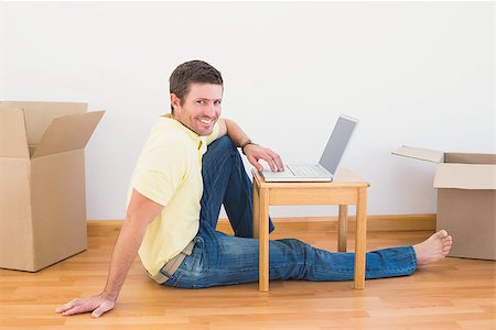 simsearch:400-07931092,k - Casual man sitting on floor using laptop on the coffee table at home in the living room Foto de stock - Super Valor sin royalties y Suscripción, Código: 400-07931085