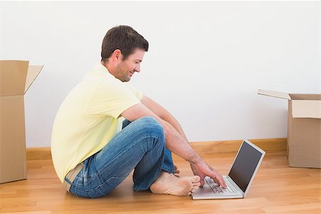 simsearch:400-07931092,k - Casual man sitting on floor using laptop at home in the living room Foto de stock - Super Valor sin royalties y Suscripción, Código: 400-07931086