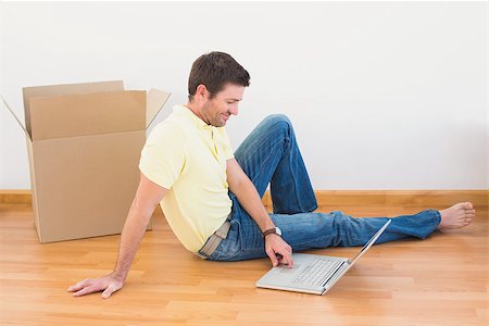 simsearch:400-07931092,k - Casual man sitting on floor using laptop at home in the living room Foto de stock - Super Valor sin royalties y Suscripción, Código: 400-07931087