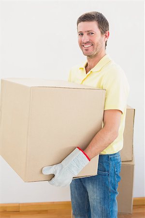 simsearch:400-07928013,k - Smiling man carrying cardboard moving boxes at home in the living room Fotografie stock - Microstock e Abbonamento, Codice: 400-07931098