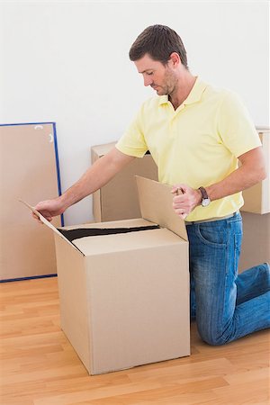 simsearch:400-07928013,k - Man open a moving box at home in the living room Fotografie stock - Microstock e Abbonamento, Codice: 400-07931100