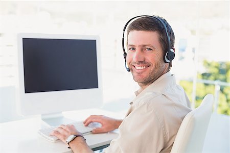 simsearch:614-00655765,k - Businessman in headset smiling at camera in his office Photographie de stock - Aubaine LD & Abonnement, Code: 400-07931112