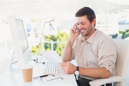 simsearch:400-07931035,k - Smiling businessman making a call and reading a document at his desk in his office Stock Photo - Budget Royalty-Free & Subscription, Code: 400-07931122
