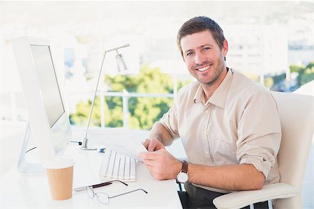 simsearch:400-07931035,k - Smiling businessman looking at document at his desk in his office Stock Photo - Budget Royalty-Free & Subscription, Code: 400-07931123