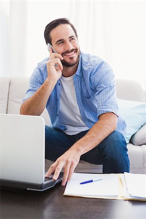simsearch:400-07333928,k - Man paying his bills with laptop while talking on phone in the living room Stock Photo - Budget Royalty-Free & Subscription, Code: 400-07931285