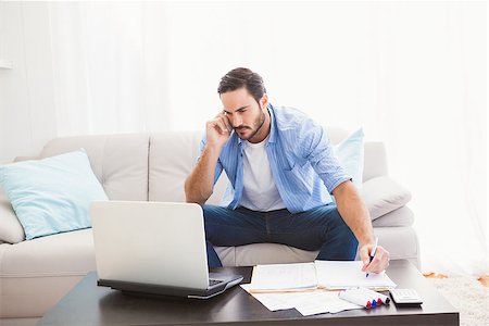 simsearch:400-07333928,k - Man paying his bills with laptop while talking on phone in the living room Stock Photo - Budget Royalty-Free & Subscription, Code: 400-07931280