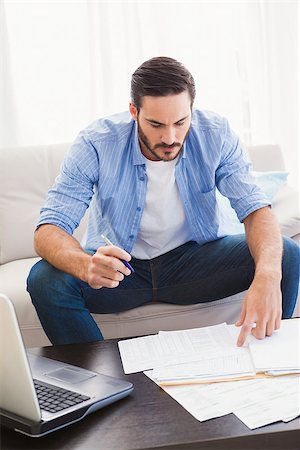 simsearch:400-07333928,k - Focused man paying his bills in the living room Stock Photo - Budget Royalty-Free & Subscription, Code: 400-07931282