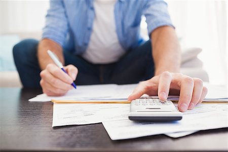 simsearch:400-07333928,k - Focused man figuring out his finances in the living room Stock Photo - Budget Royalty-Free & Subscription, Code: 400-07931283