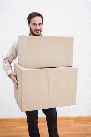 simsearch:400-07928013,k - Smiling man holding a cardboard moving box in the living room Fotografie stock - Microstock e Abbonamento, Codice: 400-07931543