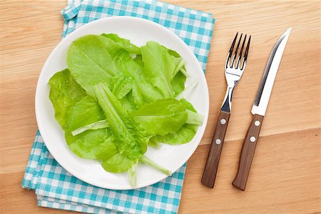 salad greens on white background - Plate with fresh salad, knife and fork. Diet food on wooden table with copy space Stock Photo - Budget Royalty-Free & Subscription, Code: 400-07933675