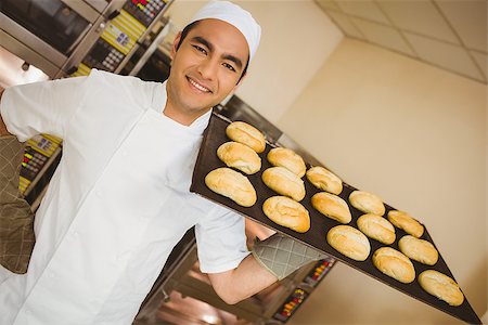 Baker smiling at camera holding tray of rolls in a commercial kitchen Stock Photo - Budget Royalty-Free & Subscription, Code: 400-07940589