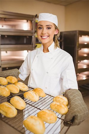 simsearch:400-07140099,k - Baker smiling at camera holding rack of rolls in a commercial kitchen Foto de stock - Royalty-Free Super Valor e Assinatura, Número: 400-07940581