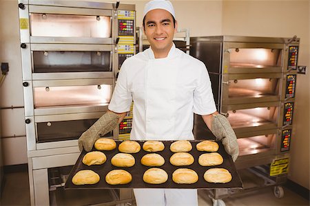Baker smiling at camera holding tray of rolls in a commercial kitchen Stock Photo - Budget Royalty-Free & Subscription, Code: 400-07940582