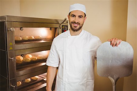 simsearch:400-07615342,k - Baker smiling at camera beside oven in a commercial kitchen Stock Photo - Budget Royalty-Free & Subscription, Code: 400-07940593