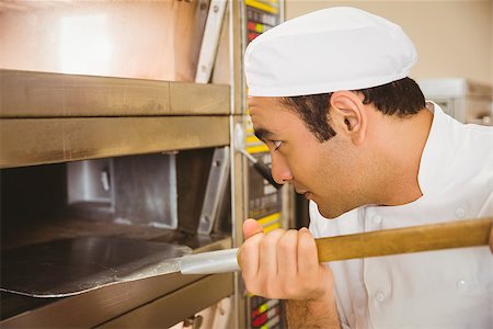 simsearch:400-07140099,k - Baker taking bread out of oven in a commercial kitchen Foto de stock - Royalty-Free Super Valor e Assinatura, Número: 400-07940607