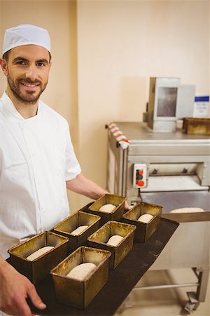 Happy baker holding tray of loaf tins in a commercial kitchen Stock Photo - Budget Royalty-Free & Subscription, Code: 400-07940634