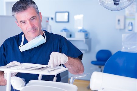 simsearch:6109-08389797,k - Dentist picking up tool and smiling at camera at the dental clinic Stock Photo - Budget Royalty-Free & Subscription, Code: 400-07940687