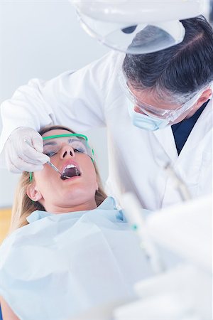 dental work - Dentist examining a patients teeth in the dentists chair at the dental clinic Stock Photo - Budget Royalty-Free & Subscription, Code: 400-07940759