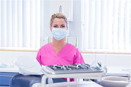 simsearch:400-07940798,k - Dentist in mask wearing pink scrubs and looking at camera at the dental clinic Stock Photo - Budget Royalty-Free & Subscription, Code: 400-07940776