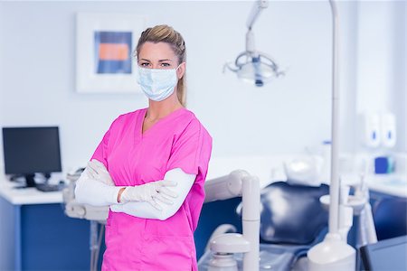 simsearch:400-07940798,k - Dentist in pink scrubs looking at camera with arms crossed at the dental clinic Stock Photo - Budget Royalty-Free & Subscription, Code: 400-07940778