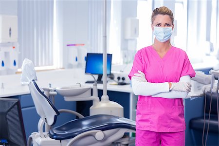 simsearch:400-07940798,k - Dentist in surgical mask standing with arms crossed at dental clinic Foto de stock - Super Valor sin royalties y Suscripción, Código: 400-07940779