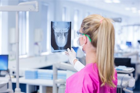 simsearch:400-07940798,k - Female dentist in pink scrubs examining x-ray at the dental clinic Stock Photo - Budget Royalty-Free & Subscription, Code: 400-07940784