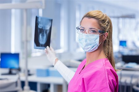 simsearch:400-07938947,k - Dentist in pink scrubs holding an x-ray and looking at camera at the dental clinic Photographie de stock - Aubaine LD & Abonnement, Code: 400-07940785