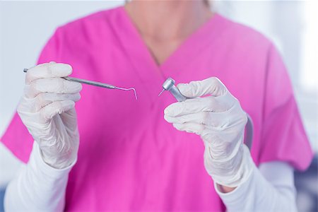simsearch:400-07940798,k - Dentist in pink scrubs holding tool at the dental clinic Stock Photo - Budget Royalty-Free & Subscription, Code: 400-07940792