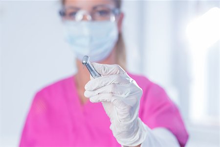 simsearch:400-07941465,k - Dentist in surgical mask and scrubs holding tool at the dental clinic Stock Photo - Budget Royalty-Free & Subscription, Code: 400-07940793