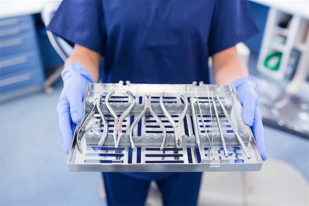 simsearch:400-07941454,k - Dentist in blue scrubs holding tray of tools at the dental clinic Stockbilder - Microstock & Abonnement, Bildnummer: 400-07940809