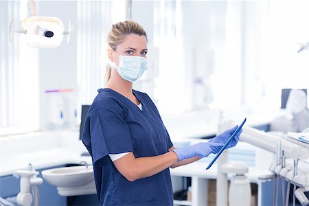 simsearch:400-07940798,k - Dentist in mask using her tablet and looking at camera at the dental clinic Stock Photo - Budget Royalty-Free & Subscription, Code: 400-07940816