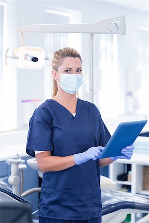 simsearch:400-07940798,k - Dentist in mask using her tablet and looking at camera at the dental clinic Stock Photo - Budget Royalty-Free & Subscription, Code: 400-07940817