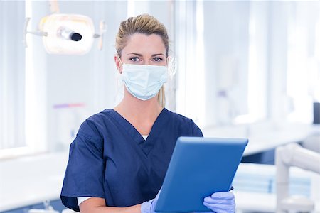 simsearch:400-07940798,k - Dentist in mask using her tablet and looking at camera at the dental clinic Stock Photo - Budget Royalty-Free & Subscription, Code: 400-07940818